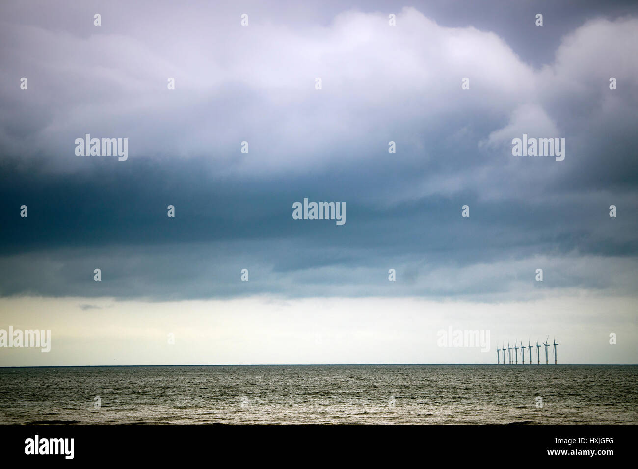 Estate tempestose nuvole sopra il mare Iris con una linea di turbine eoliche all'orizzonte visto dal popolare cittadina turistica di Rhyl, Denbighshire, Galles Foto Stock