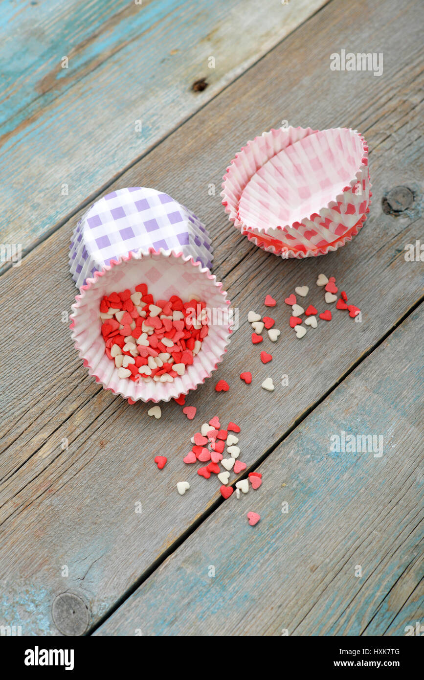 Colore candy cuori con cupcake casi su sfondo di legno Foto Stock