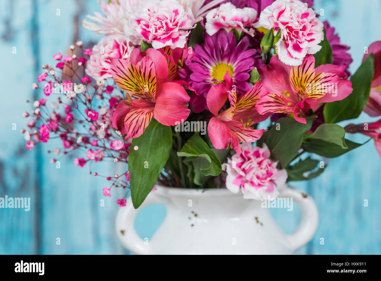 Bouquet di fiori in un vaso vintage con blu sullo sfondo di legno Foto Stock