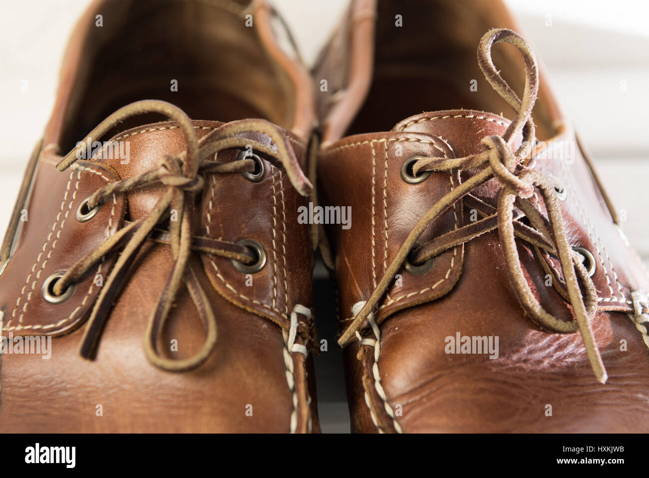 Coppia di usurati brown casual scarpe in pelle di fronte bianco sullo sfondo di legno Foto Stock