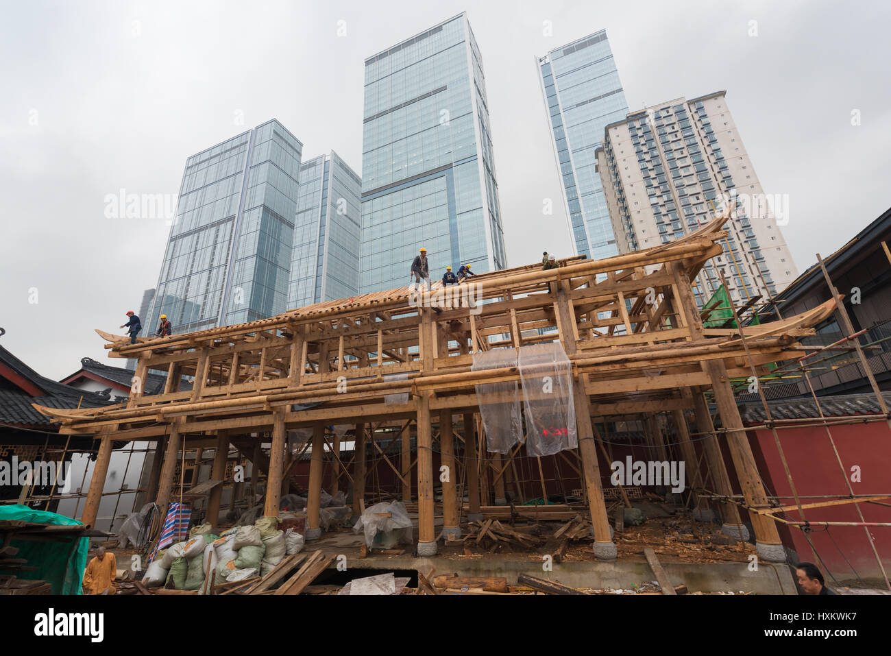 Chengdu, provincia del Sichuan, Cina - 13 novembre 2015: Operai in un tempio in stile antico in costruzione di fronte ai moderni grattacieli Foto Stock