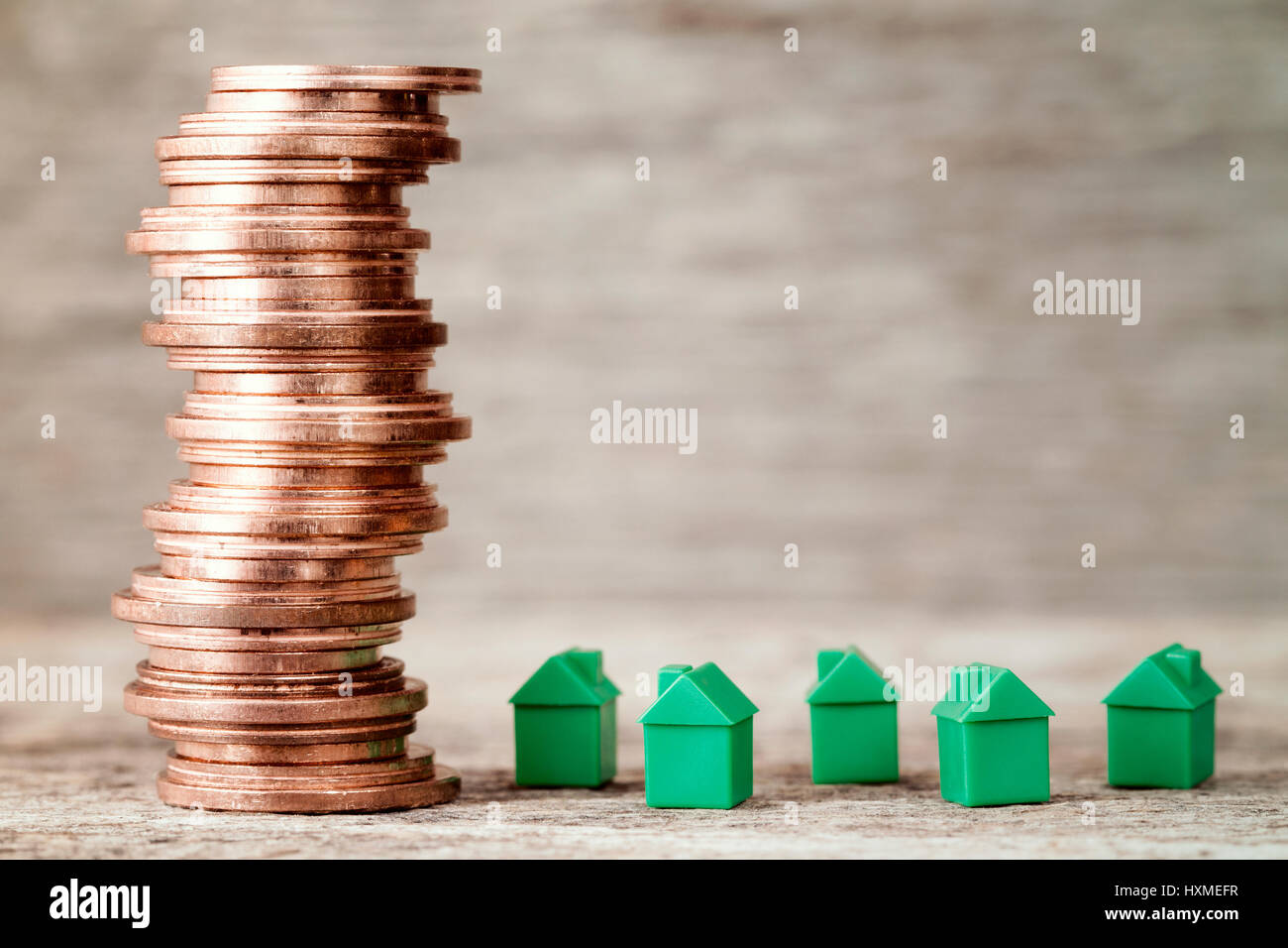 Case in miniatura e monete di rame stack. Concetto di proprietà per scaletta, ipotecari e immobiliari Investimenti Foto Stock