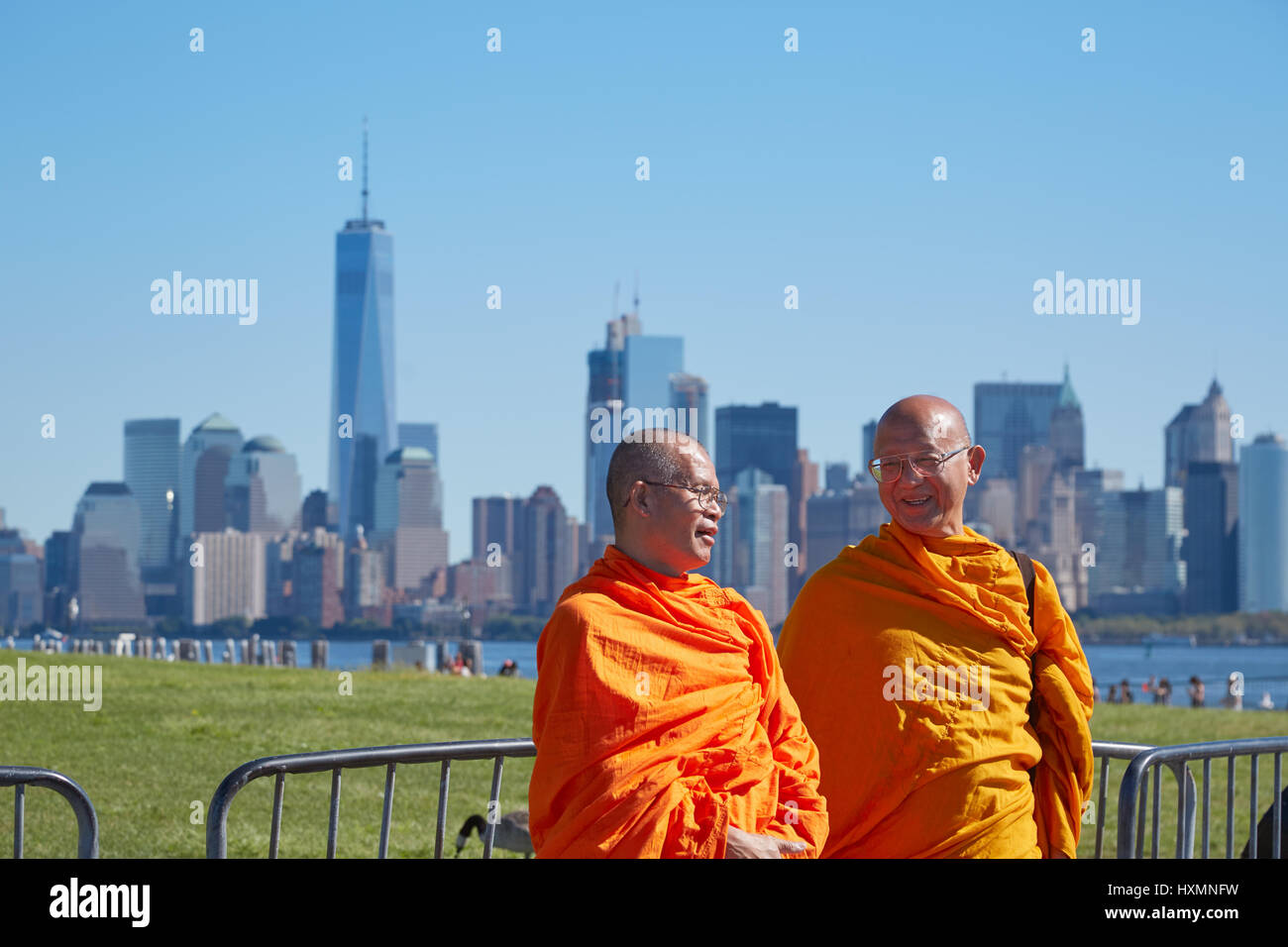 Due monaci buddisti con abito arancione nella parte anteriore di New York skyline della città in una giornata di sole e cielo blu Foto Stock