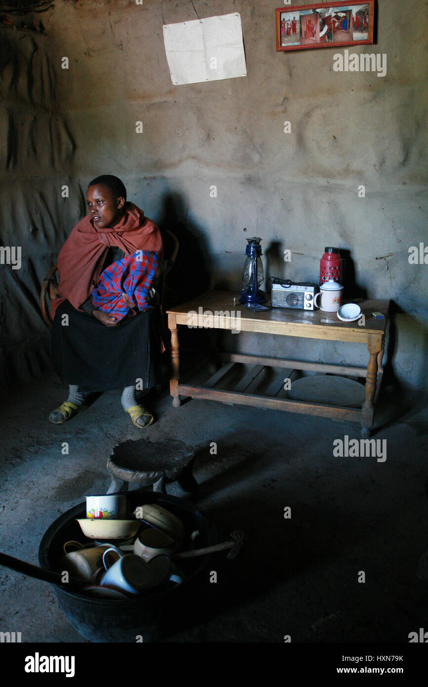 Meserani Snake Park, Arusha, Tanzania - Febbraio 14, 2008: vista interna della casa e semplice dei beni di persone africane tribù Masai, giovane donna sit Foto Stock