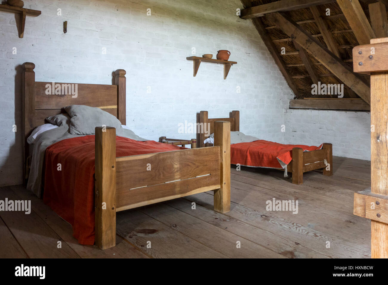Camera dei bambini con grandi cuscini e coperte rosso colorato con robbia in casa medioevale Foto Stock