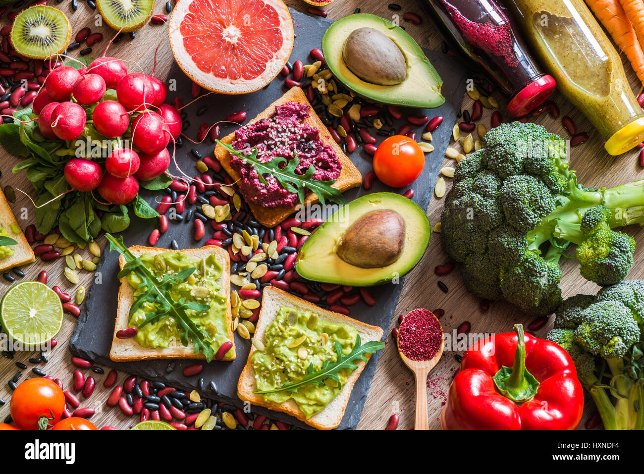 Sano cibo vegan. Panini e verdure fresche su sfondo di legno. Detox dieta. Colorati diversi succhi di frutta freschi. vista superiore Foto Stock