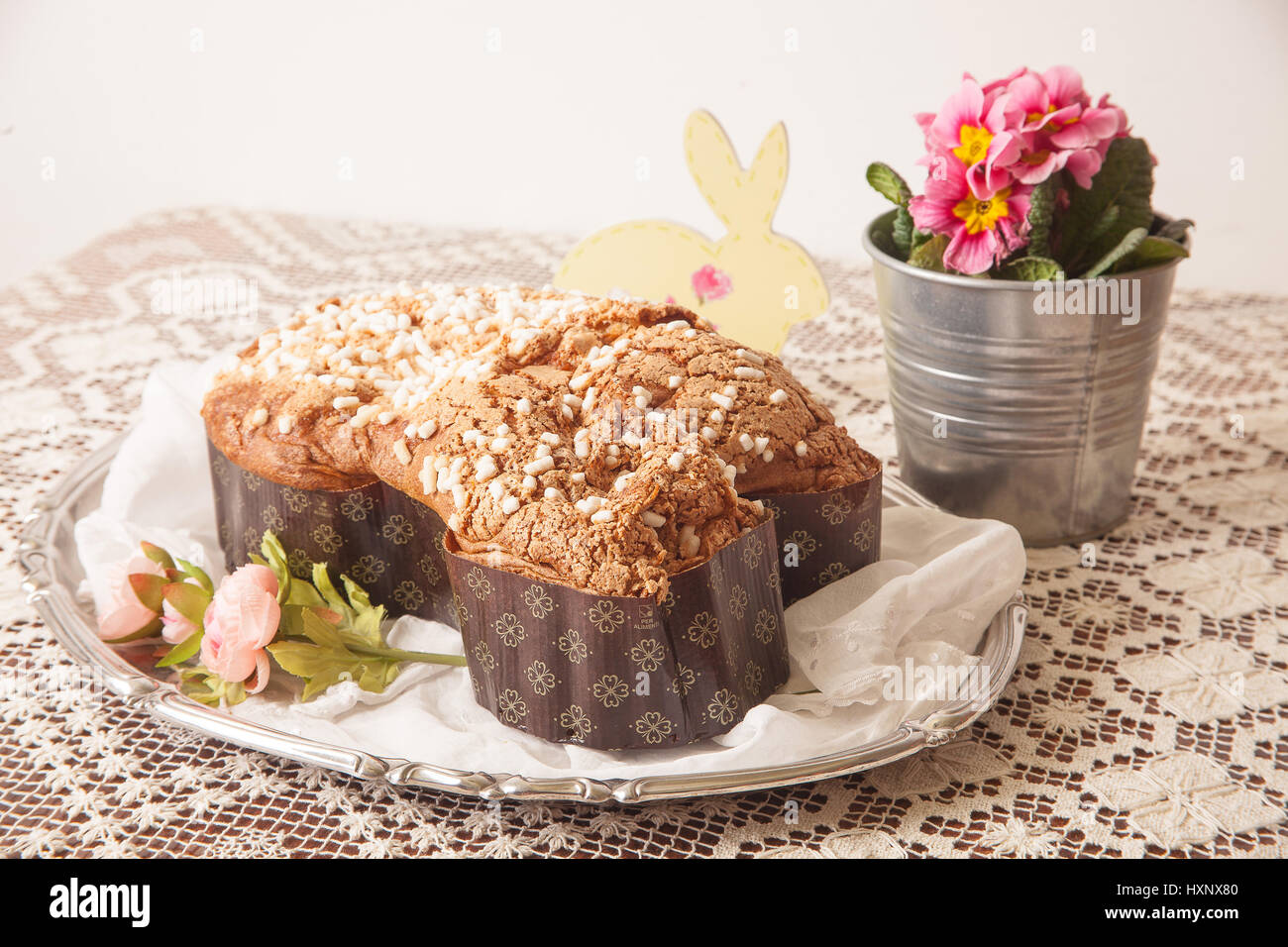 Colomba di pasqua su una scheda con tovaglia di pizzo e un vaso con primule. Foto Stock