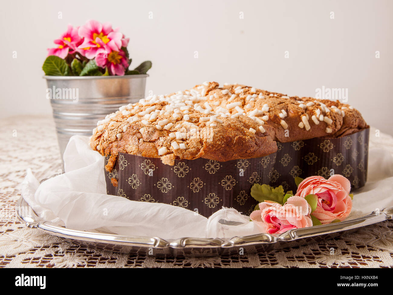 Colomba di pasqua su una scheda con tovaglia di pizzo e un vaso con primule. Foto Stock