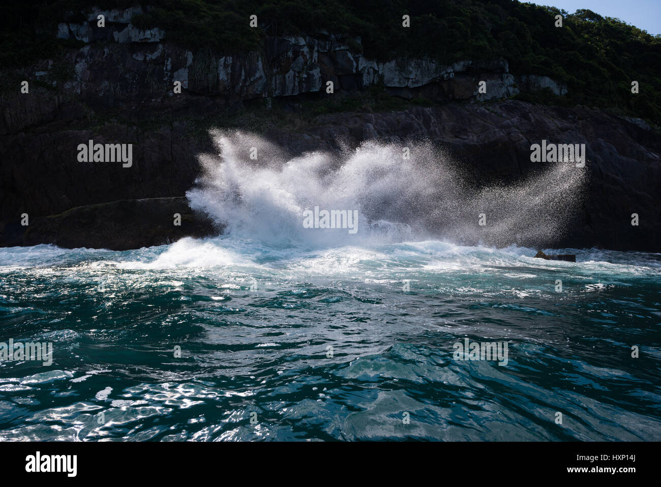 Un'onda si blocca su scogliere rocciose del Ilhabela Foto Stock