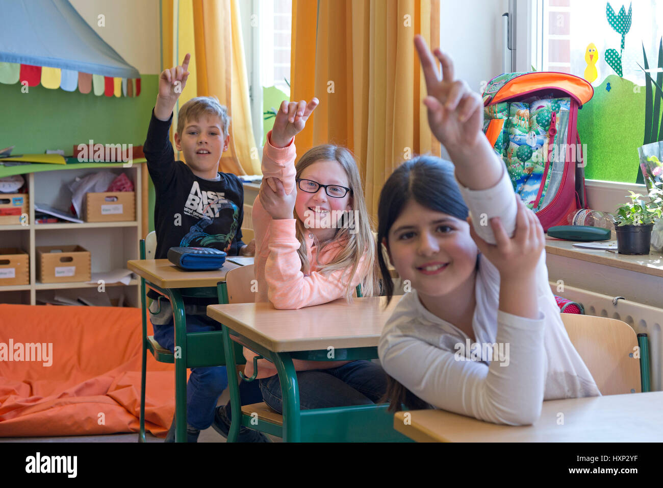 I bambini ad alzare la mano presso la scuola primaria Foto Stock