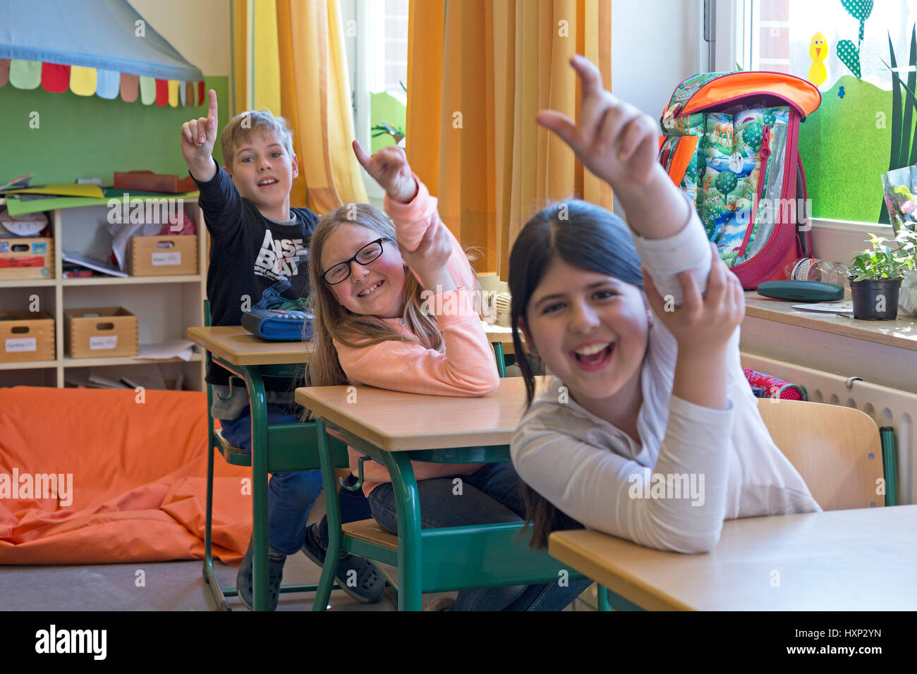 I bambini ad alzare la mano presso la scuola primaria Foto Stock
