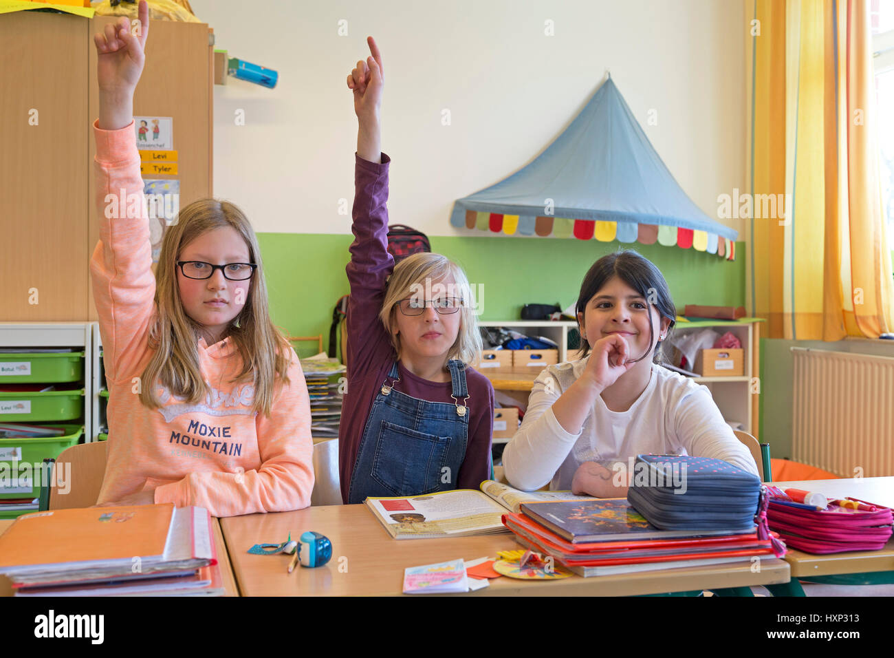 I bambini ad alzare la mano presso la scuola primaria Foto Stock