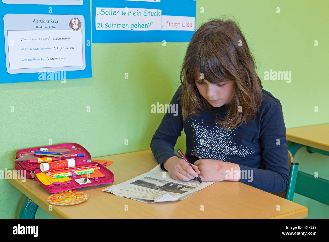 Ragazza di scrivere un test presso la scuola primaria Foto Stock