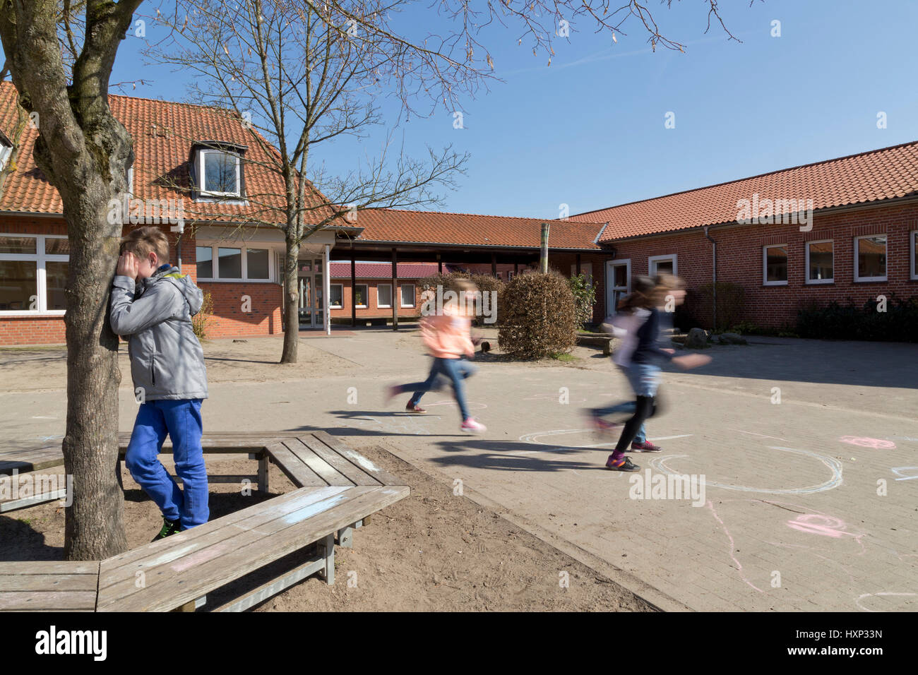 I bambini presso la scuola primaria di giocare a nascondino durante la pausa Foto Stock