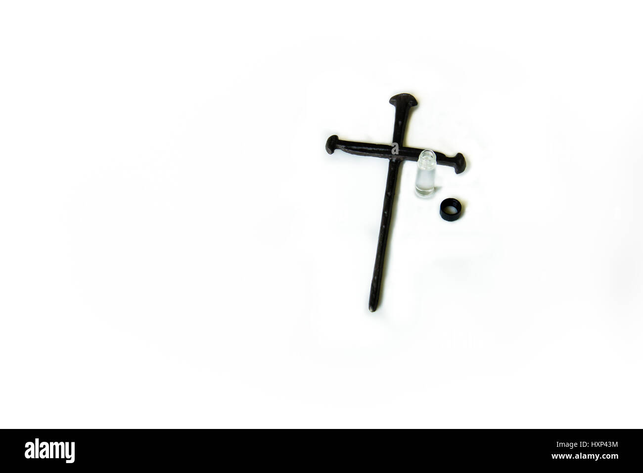 Chiodo spiked croce con olio di unzione accanto ad esso su una bianca su sfondo. Foto Stock
