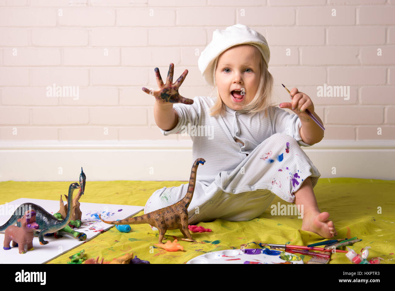 Bambina aventi gioco disordinato con vernici e mostrando verniciato colorato mani. Foto Stock