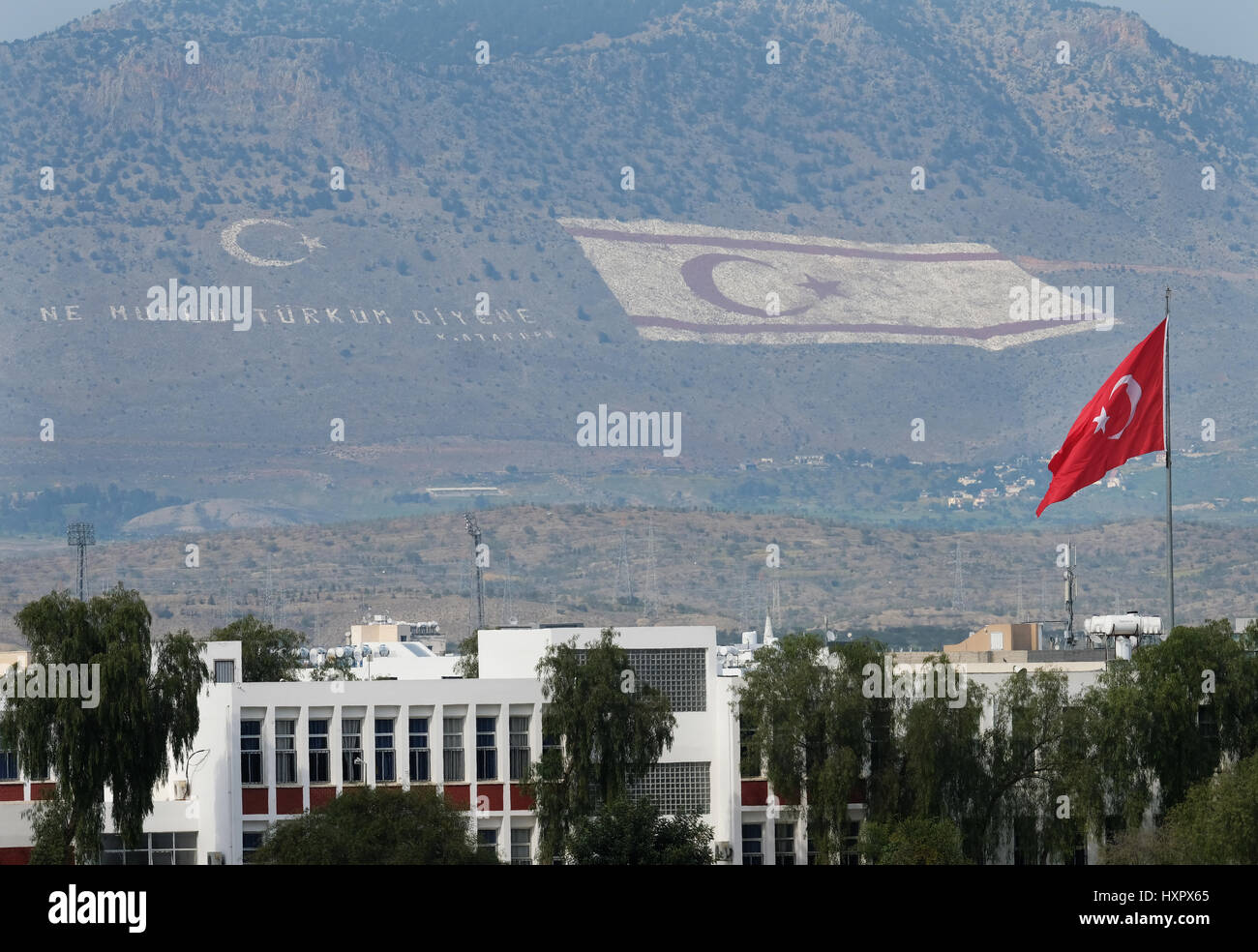 Cipro del Nord. Bandiera turca a volare su un edificio con un gigante di bandiera sul lato sud della gamma Besparmak rivolta verso Nicosia e Repubblica greca di Cipro Foto Stock
