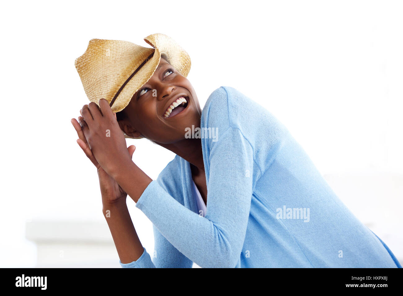 Ritratto di attraente giovane donna africana che indossa un cappello da cowboy guardando sopra la sua spalla e ridendo Foto Stock