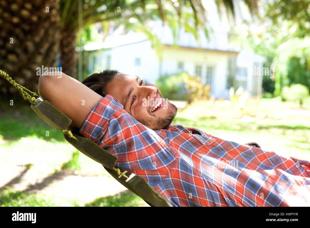Ritratto di giovane attraente uomo disteso in amaca e sorridente Foto Stock