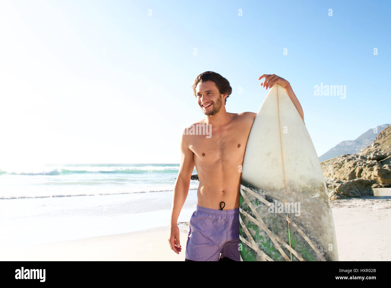 Ritratto di felice surfista maschio in piedi con la sua pensione presso la spiaggia Foto Stock