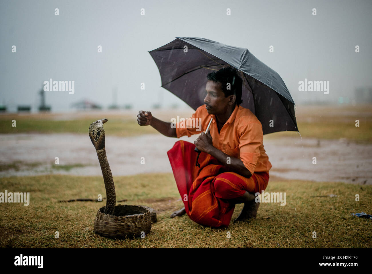 Un serpente incantatore in Colombo, Sri Lanka in attesa di intrattenere i passanti comprare per una piccola tassa. Il serpente è un cobra. Foto Stock