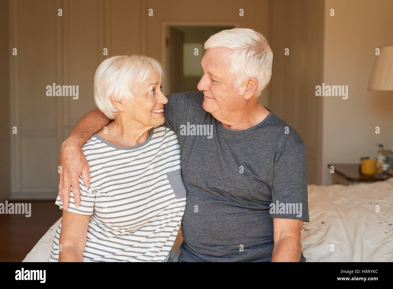 Sorridente e affettuosa coppia senior seduta sul letto insieme Foto Stock