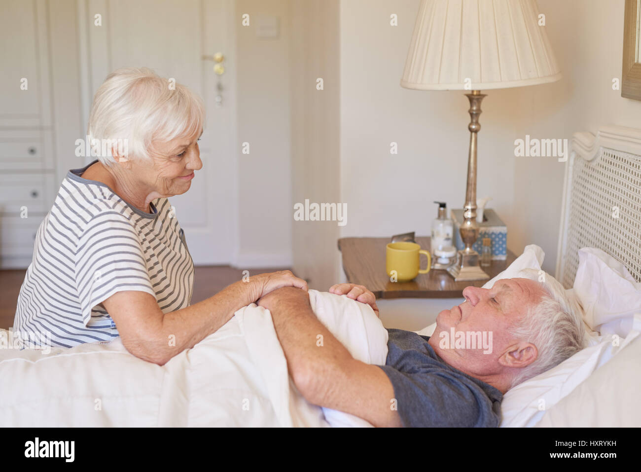 Senior donna di prendersi cura di suo marito malato a letto Foto Stock