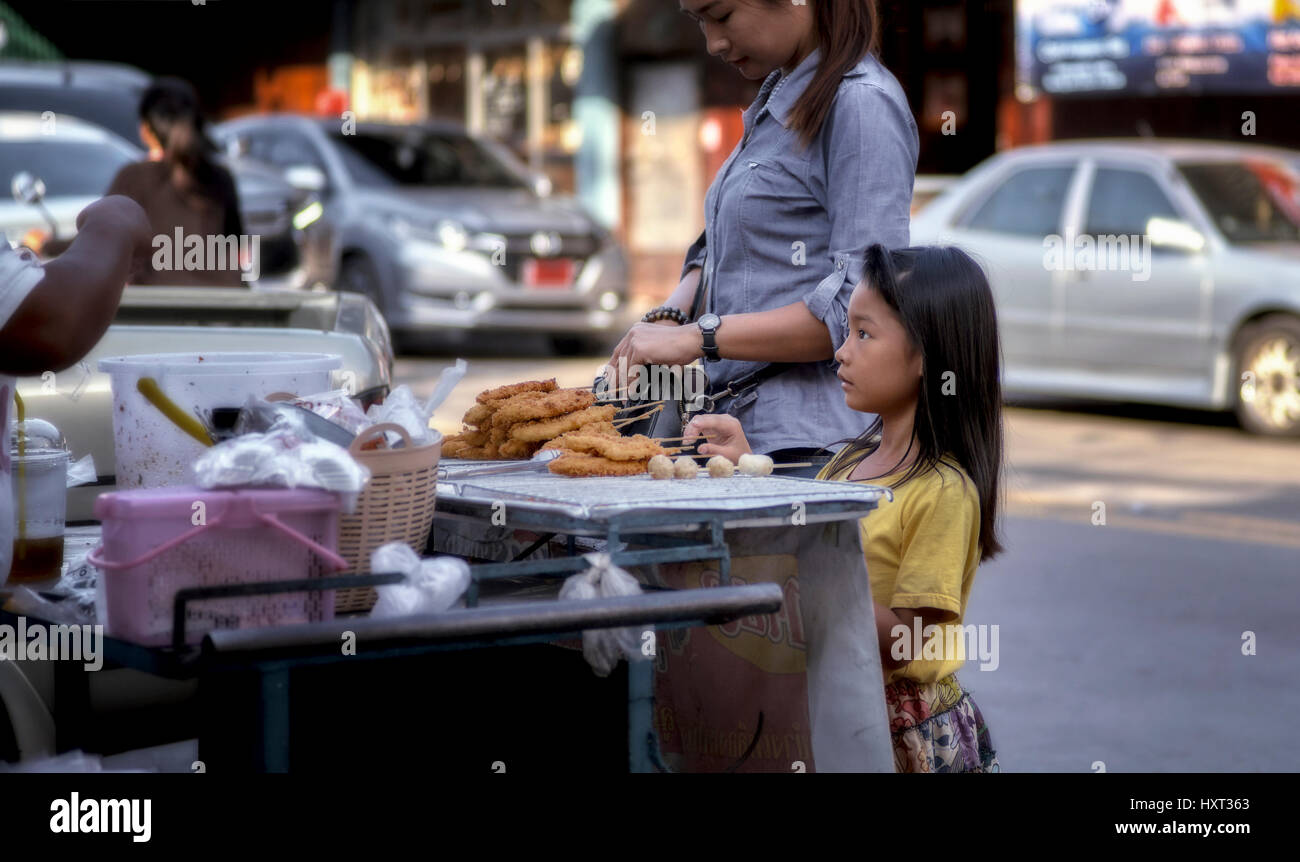 Innocenza nel viso di un bambino. Thailandia bambino shopping con sua madre in un carrello cibo di strada tailandese. Sud-est asiatico Foto Stock