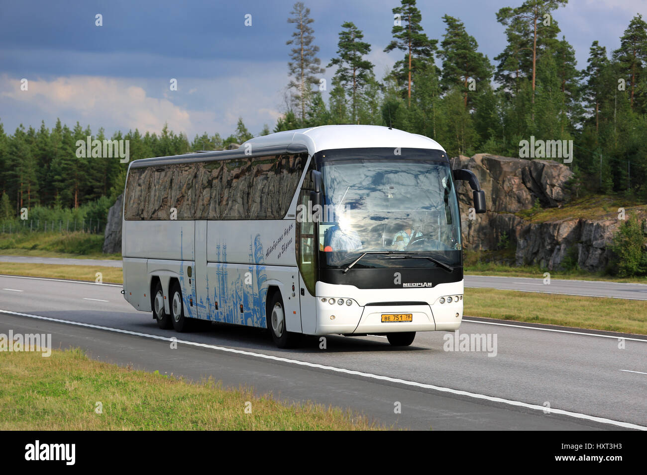 PAIMIO, Finlandia - Agosto 19, 2016: Bianco Neoplan Tourliner pullman si muove lungo l'autostrada nel paesaggio rurale del sud della Finlandia. Foto Stock