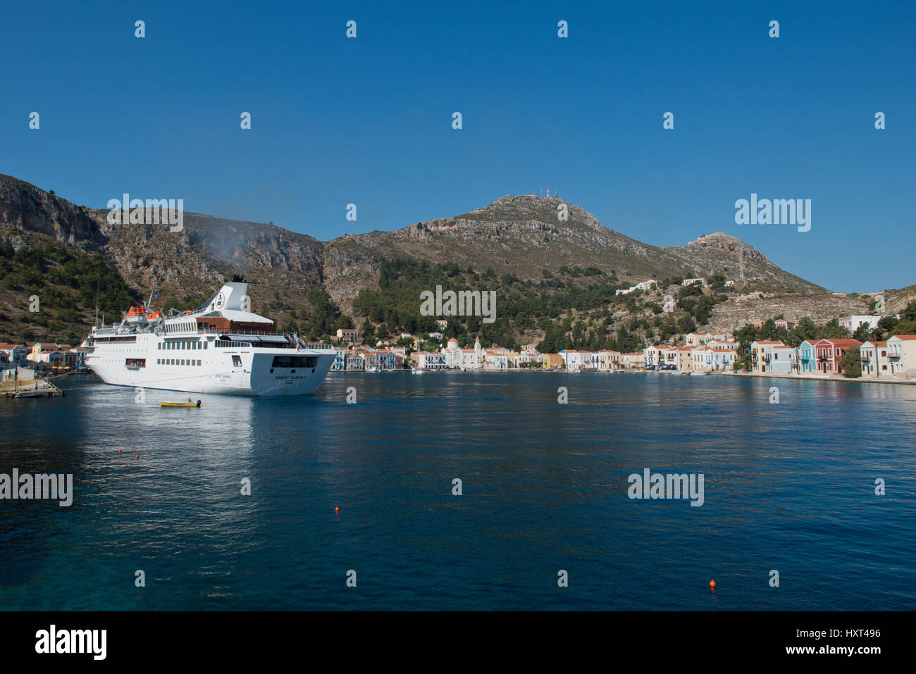 Hafensicht mit bunten Häusern, großer weißer Yacht und kahlen Bergen, Insel Kastellorizo, Dodekanes, Griechenland Foto Stock