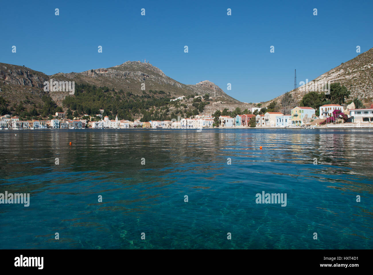 Hafen, weite Bucht türkisem mit Wasser, Reihe von bunten Häusern und kahlen Bergen, Insel Kastellorizo, Dodekanes, Griechenland Foto Stock