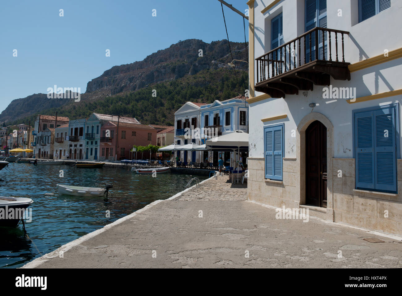 Hafenquai mit bunten Häusern und Bergen im Hintergrund, weißes Haus mit blauen Fensterläden und Balkon, Insel Kastellorizo, Dodekanes, Griechenland Foto Stock