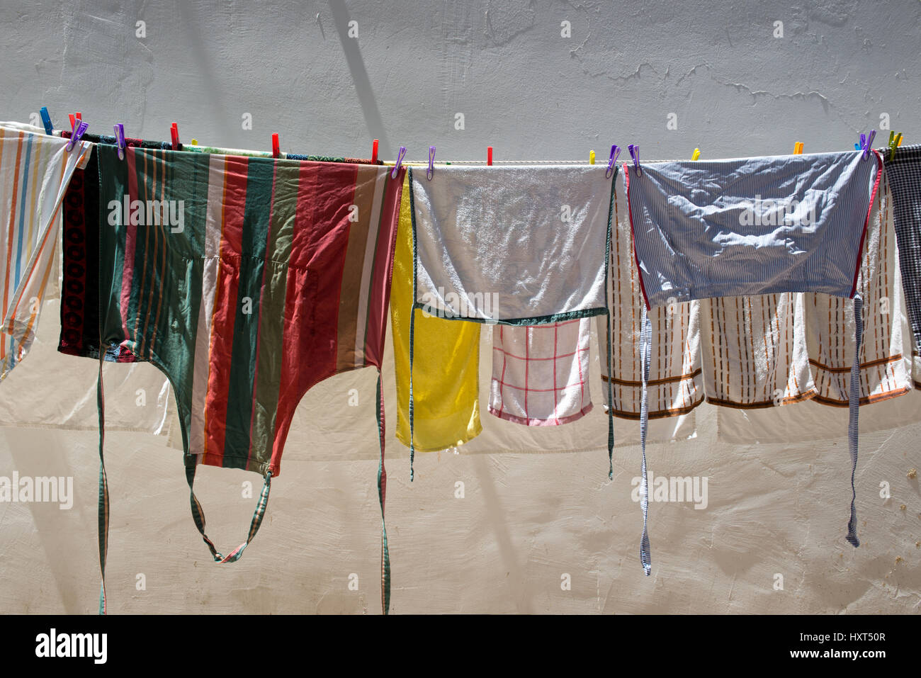 Bunte Wäsche auf einer Wäscheleine vor weißer Wand von Sonne angestrahlt, Insel Kastellorizo, Dodekanes, Griechenland Foto Stock