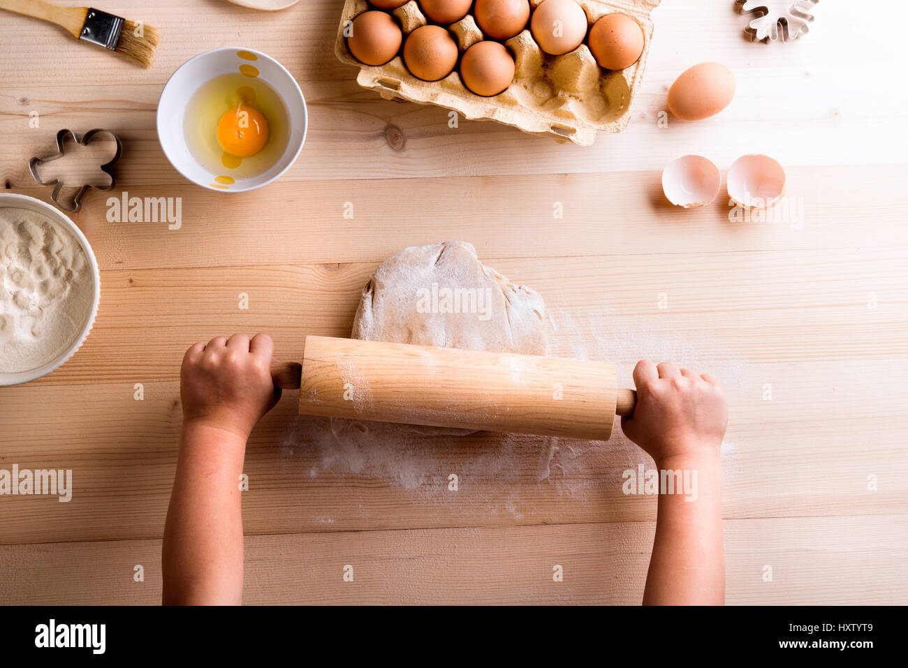 Festa della mamma composizione. Le mani di un irriconoscibile girl i biscotti di cottura, stendere la pasta sul tavolo. Studio shot su sfondo di legno. Foto Stock