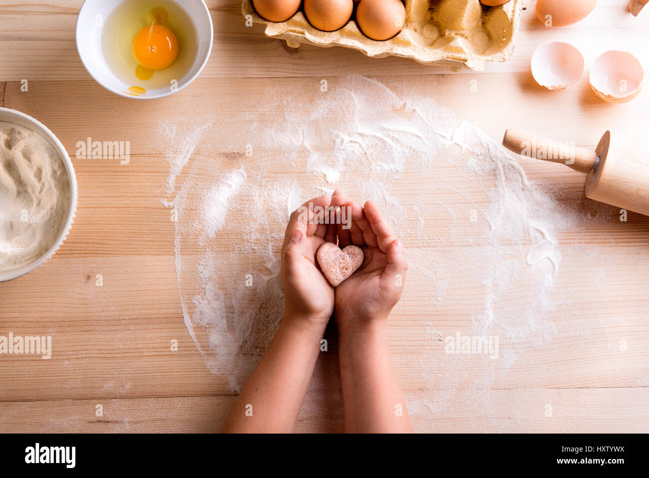 Festa della mamma composizione. Le mani di un irriconoscibile ragazza con cuore di pasticceria. Studio shot su sfondo di legno. Foto Stock