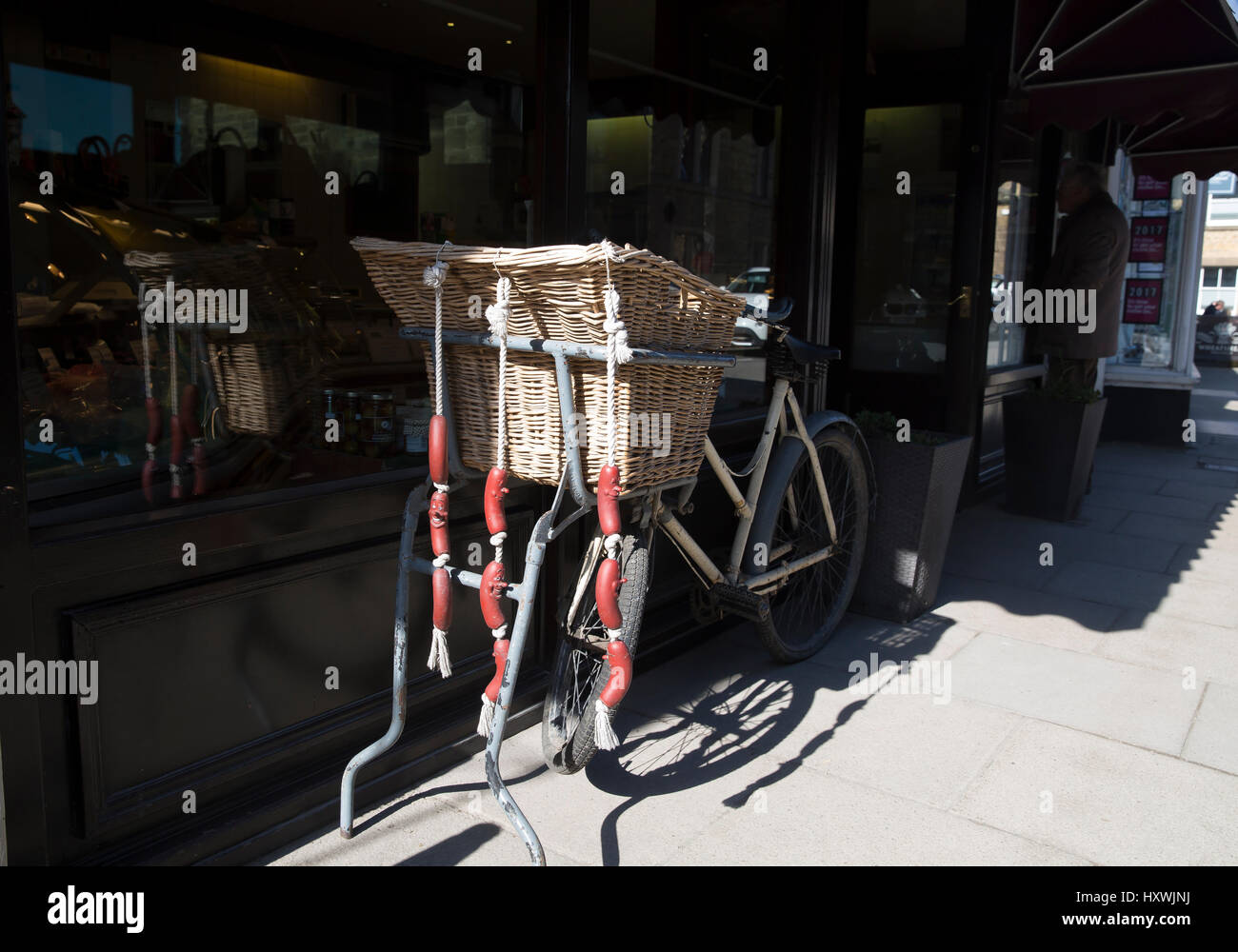 Moto parcheggiate fuori un macellaio con una stringa di salami appesi al cestello in Buxton Derbyshire Foto Stock