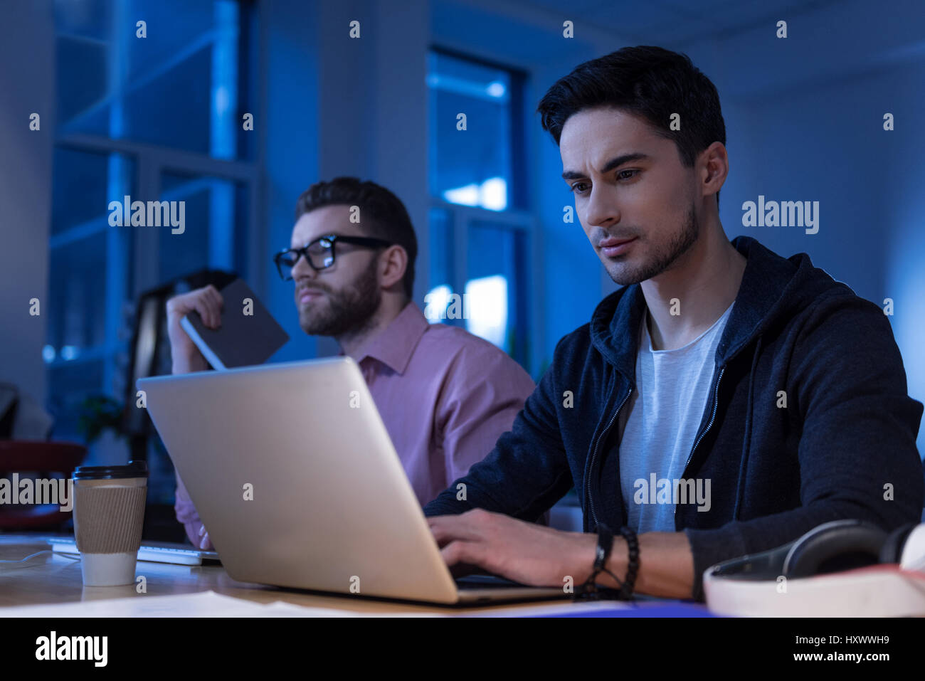 Attraente programmatore barbuto digitando sul laptop Foto Stock