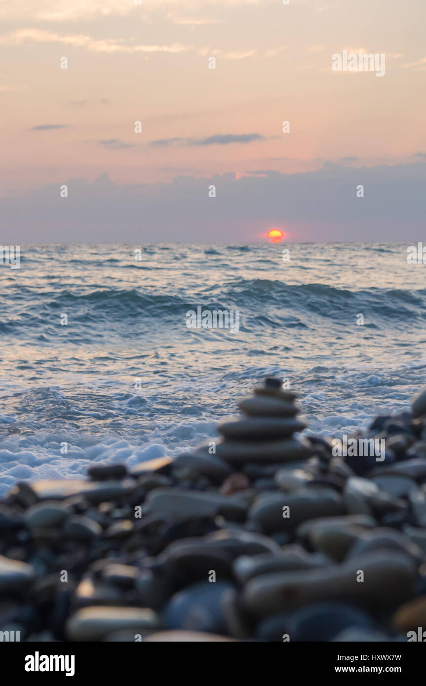 Piramide piegata Zen pietre ghiaia sul mare spiaggia al tramonto Foto Stock
