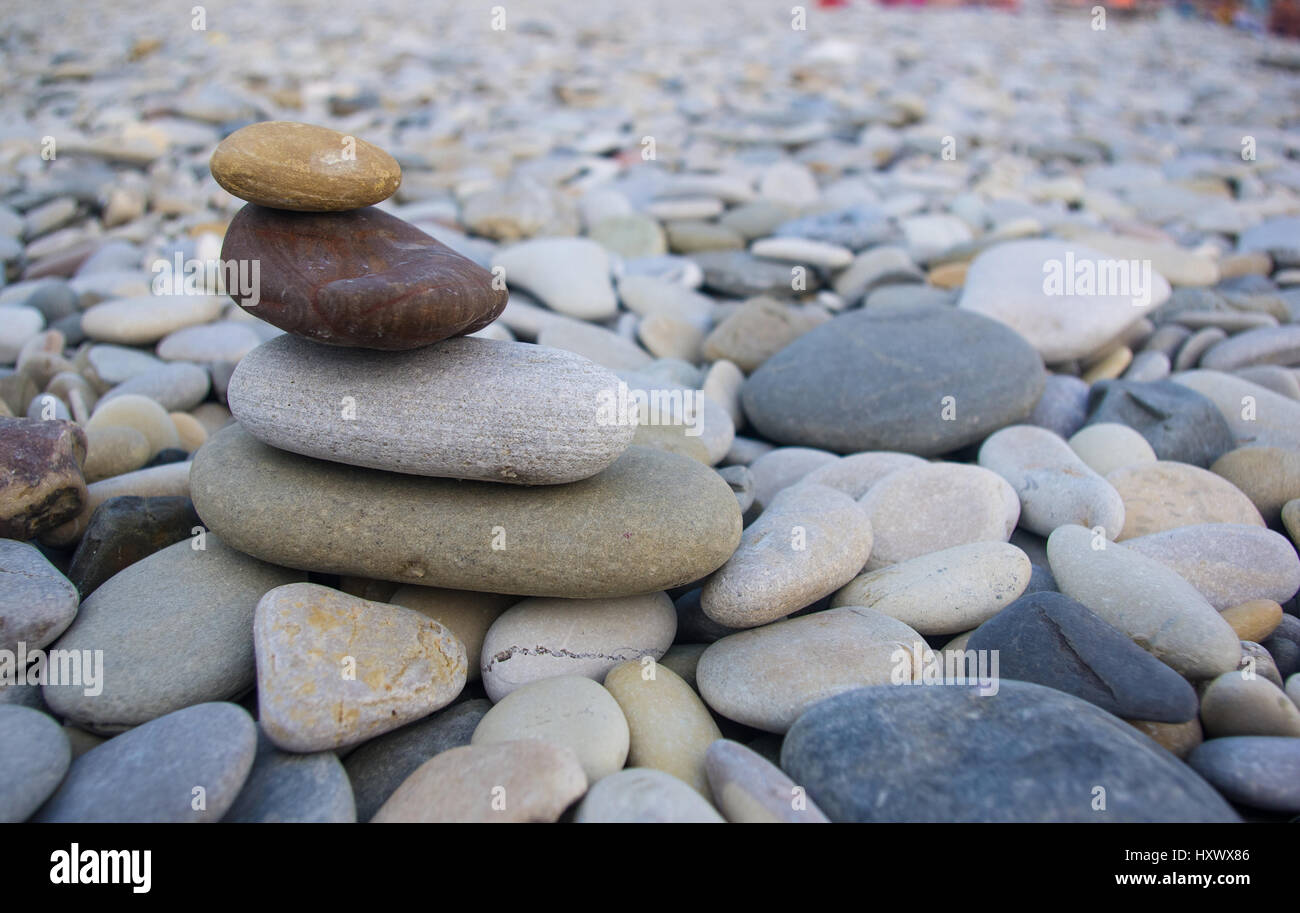 Piramide piegata Zen pietre ghiaia sul mare spiaggia al tramonto Foto Stock