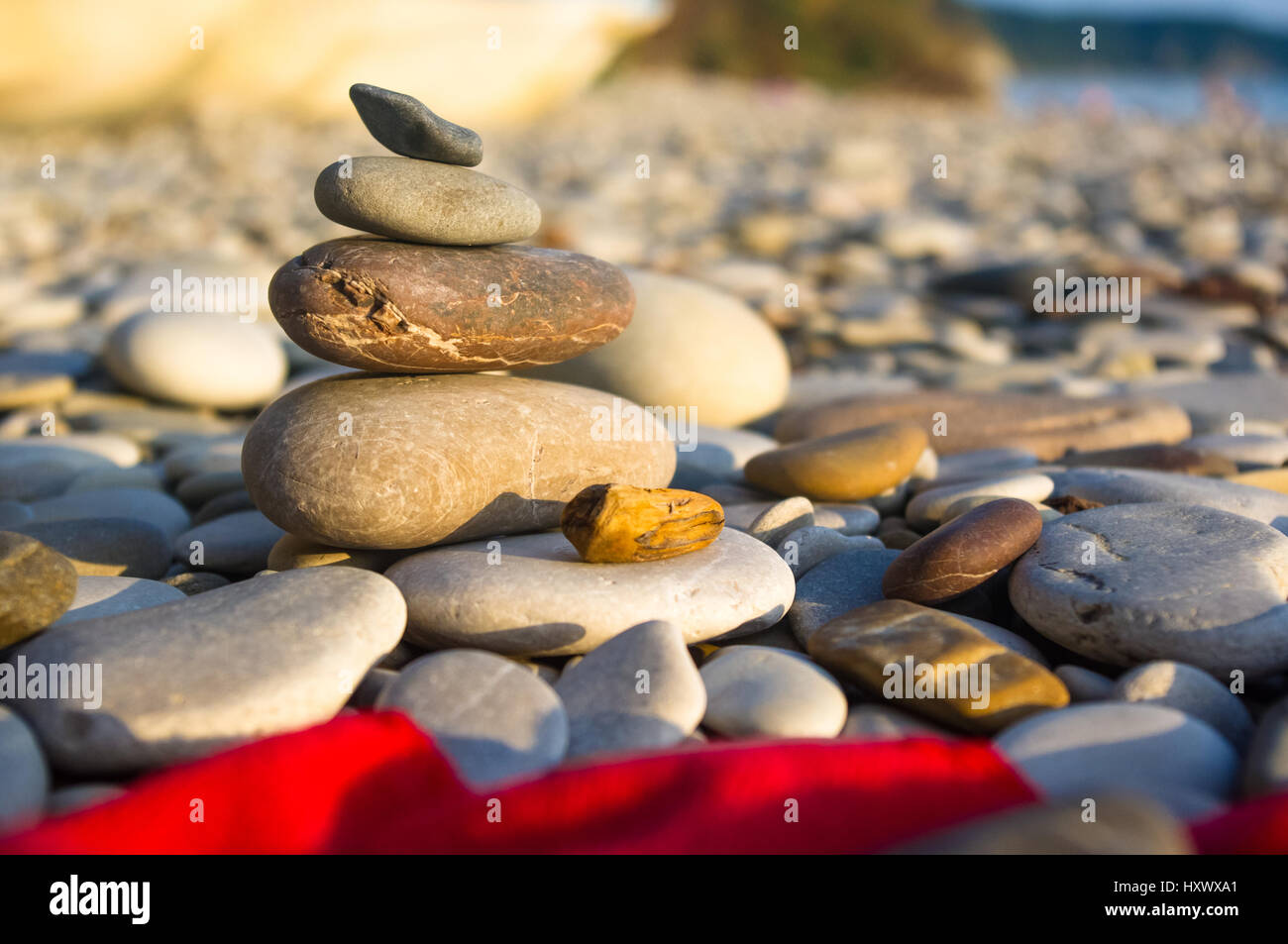 Piramide piegata Zen pietre ghiaia sul mare spiaggia al tramonto Foto Stock