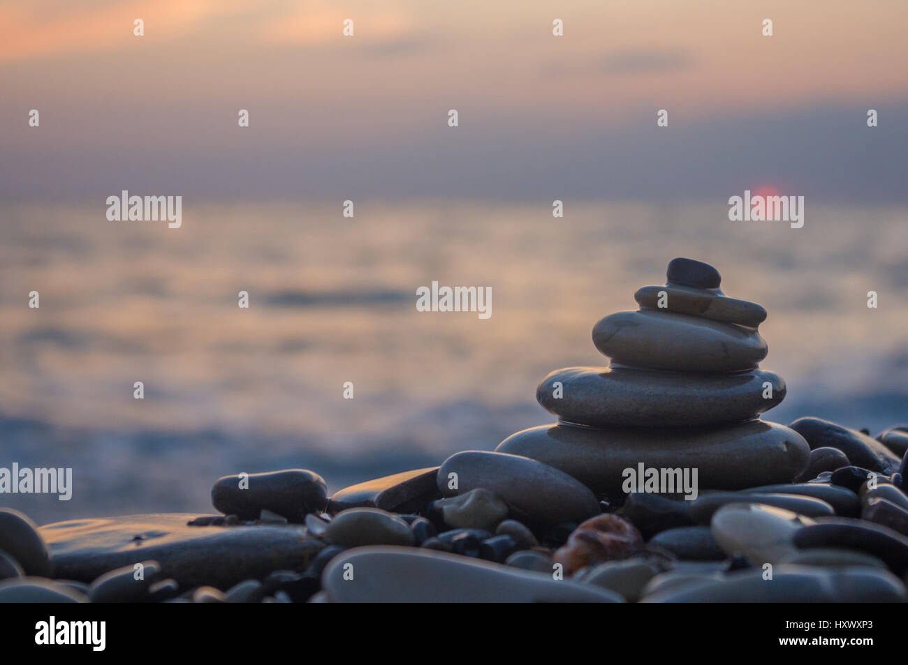 Piramide piegata Zen pietre ghiaia sul mare spiaggia al tramonto Foto Stock