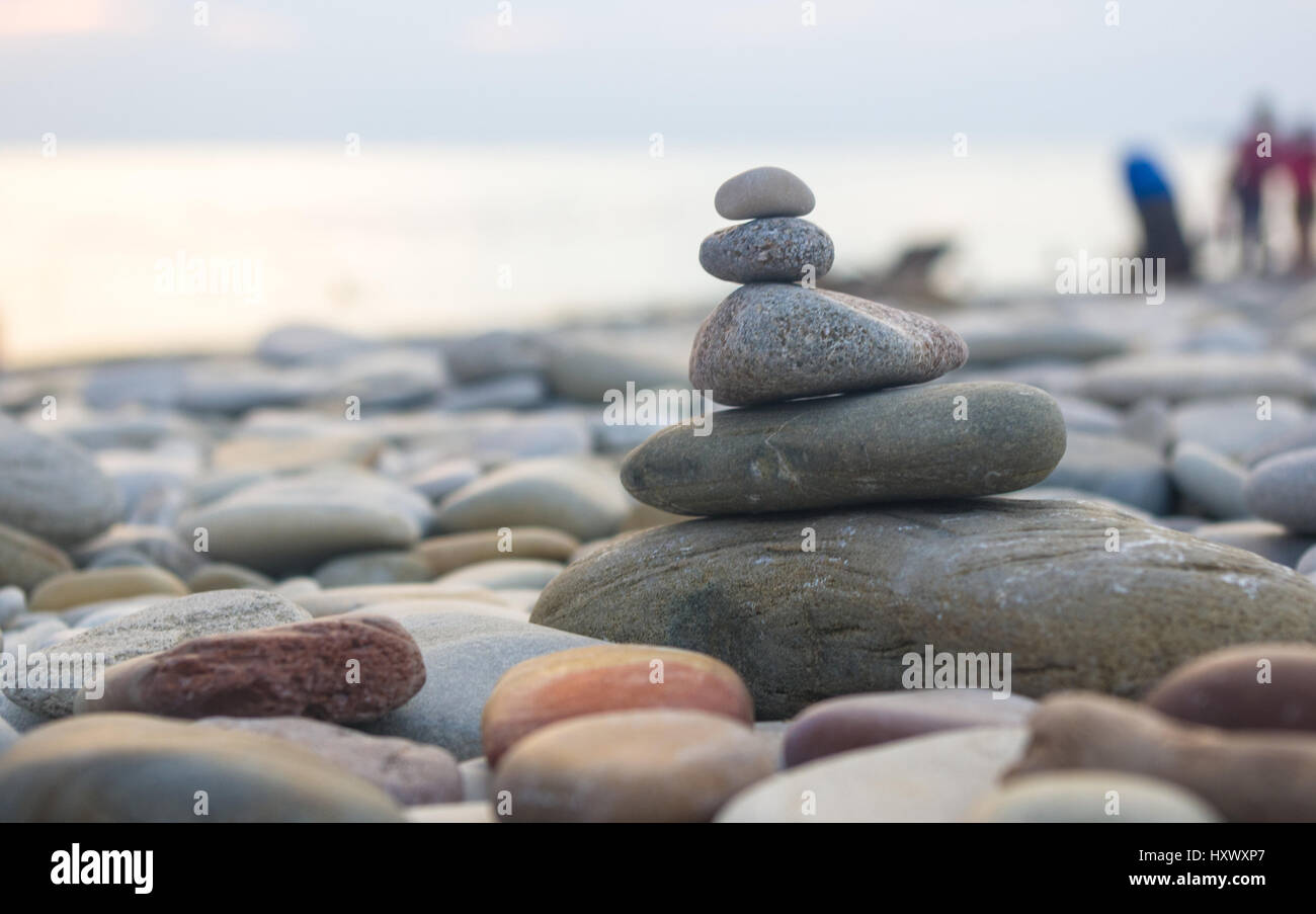 Piramide piegata Zen pietre ghiaia sul mare spiaggia al tramonto Foto Stock