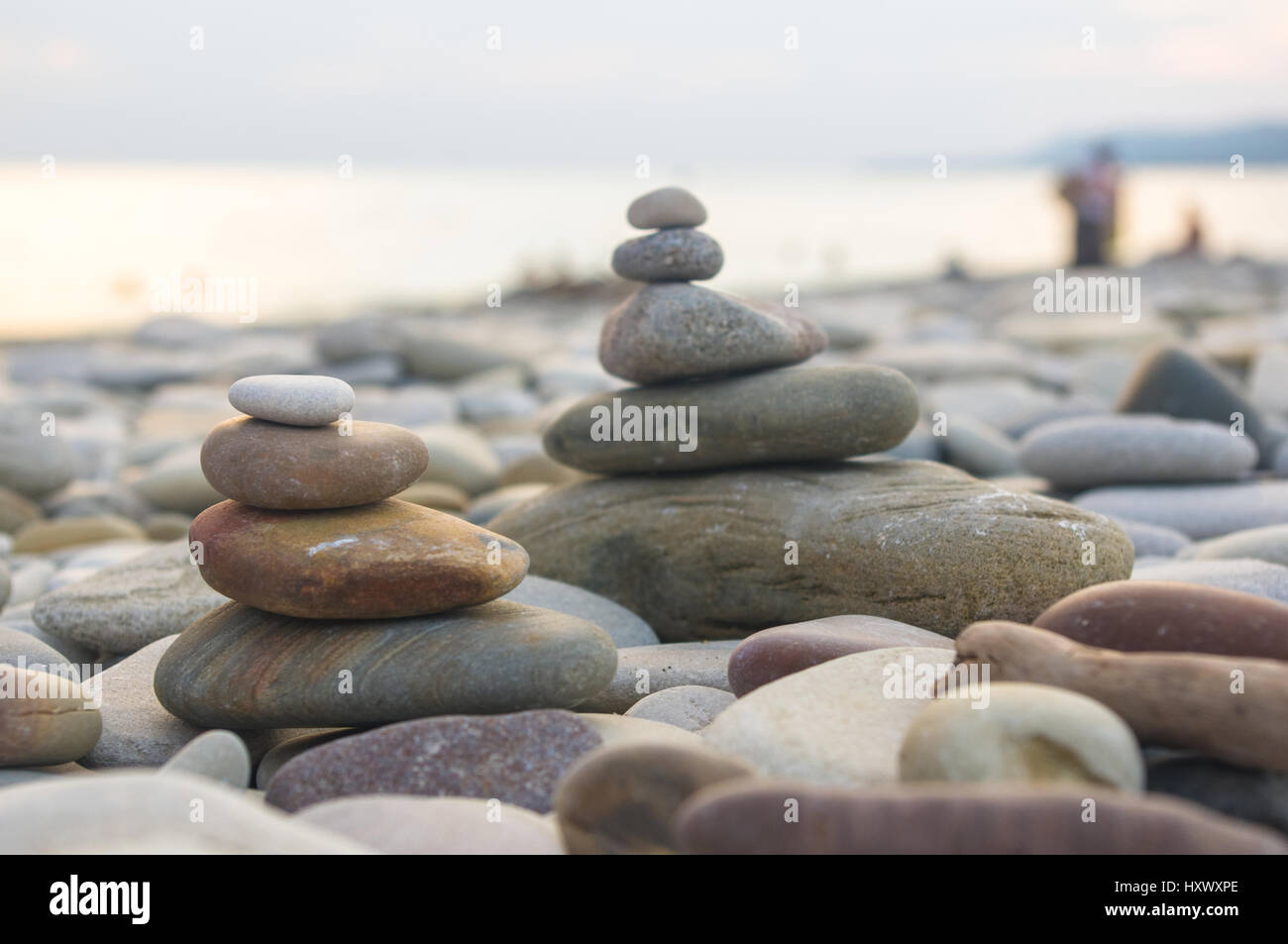 Piramide piegata Zen pietre ghiaia sul mare spiaggia al tramonto Foto Stock