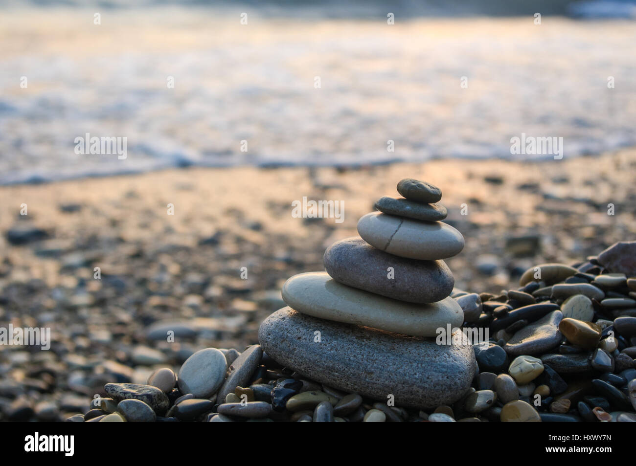 Piramide piegata Zen pietre ghiaia sul mare spiaggia al tramonto Foto Stock