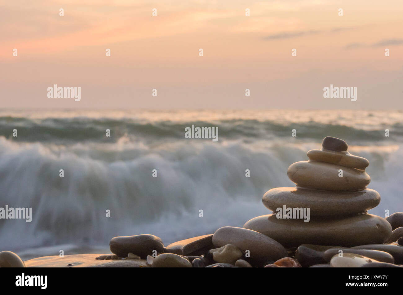 Piramide piegata Zen pietre ghiaia sul mare spiaggia al tramonto Foto Stock