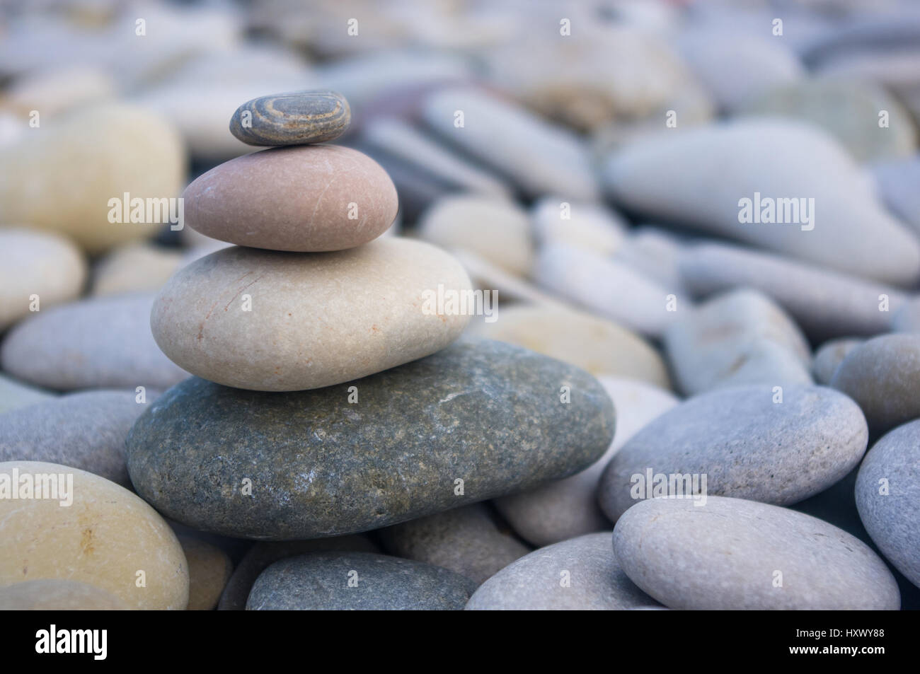 Piramide piegata Zen pietre ghiaia sul mare spiaggia al tramonto Foto Stock