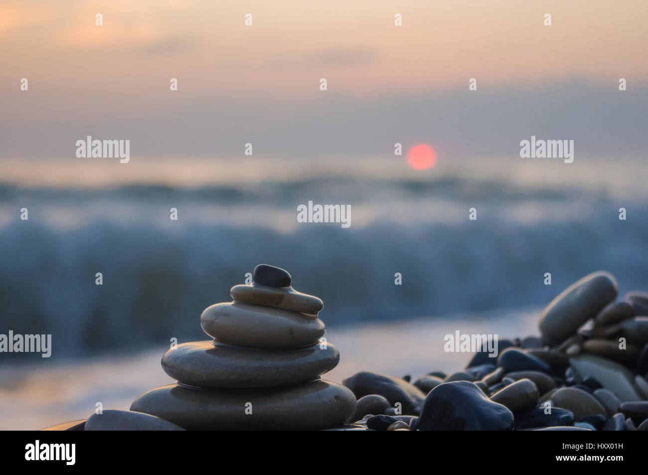 Piramide piegata Zen pietre ghiaia sul mare spiaggia al tramonto Foto Stock