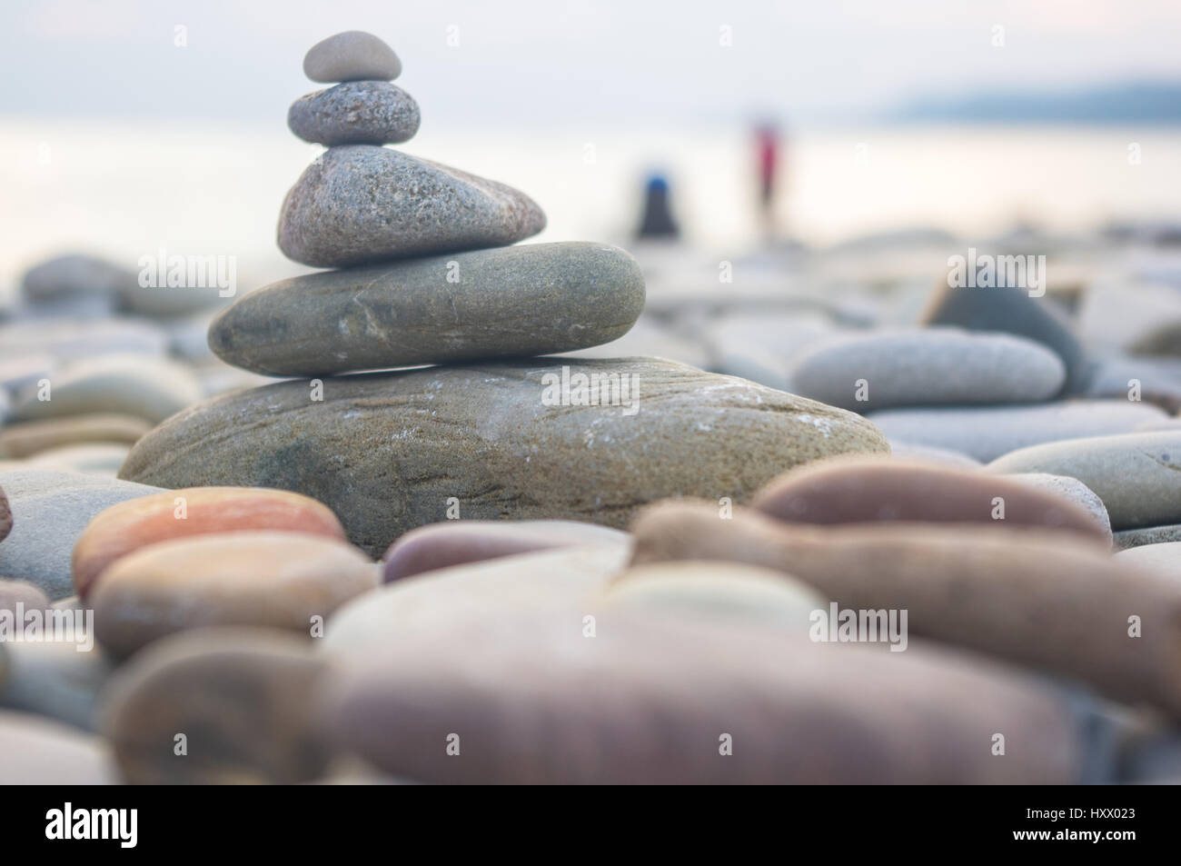 Piramide piegata Zen pietre ghiaia sul mare spiaggia al tramonto Foto Stock