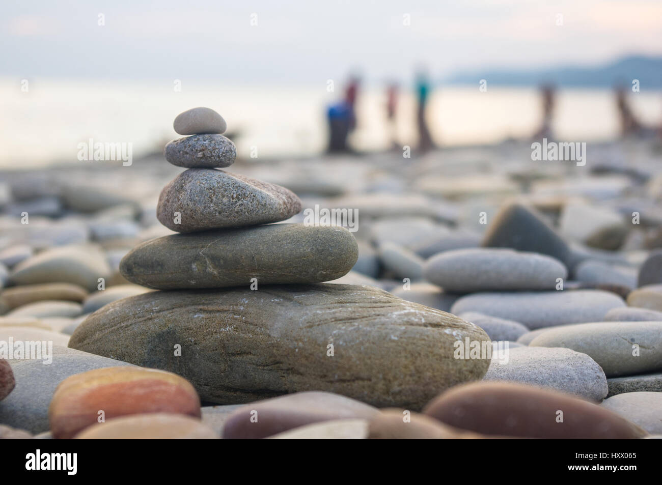 Piramide piegata Zen pietre ghiaia sul mare spiaggia al tramonto Foto Stock