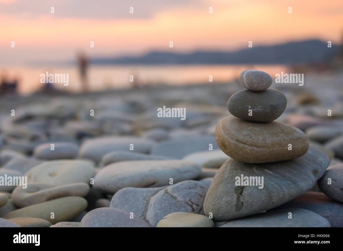 Piramide piegata Zen pietre ghiaia sul mare spiaggia al tramonto Foto Stock